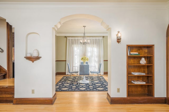 entryway with a chandelier, light hardwood / wood-style flooring, and ornamental molding