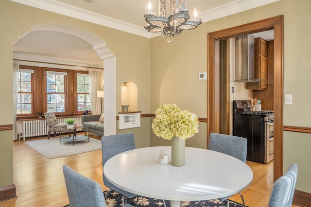 dining room with a notable chandelier, light wood-type flooring, crown molding, and radiator