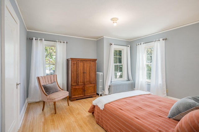 bedroom with light hardwood / wood-style floors, radiator, and multiple windows