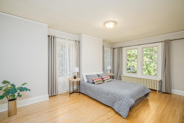 bedroom featuring crown molding, radiator heating unit, and hardwood / wood-style floors