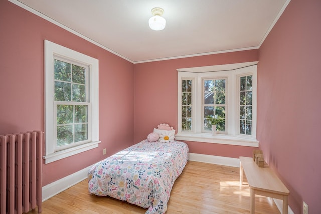 bedroom featuring radiator, crown molding, multiple windows, and light wood-type flooring