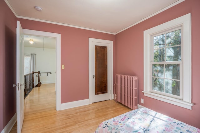 bedroom with a closet, light wood-type flooring, radiator heating unit, and multiple windows