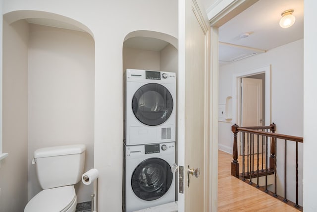 laundry room with hardwood / wood-style floors and stacked washer and clothes dryer