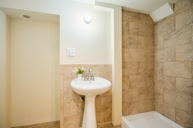 bathroom featuring lofted ceiling and tile walls