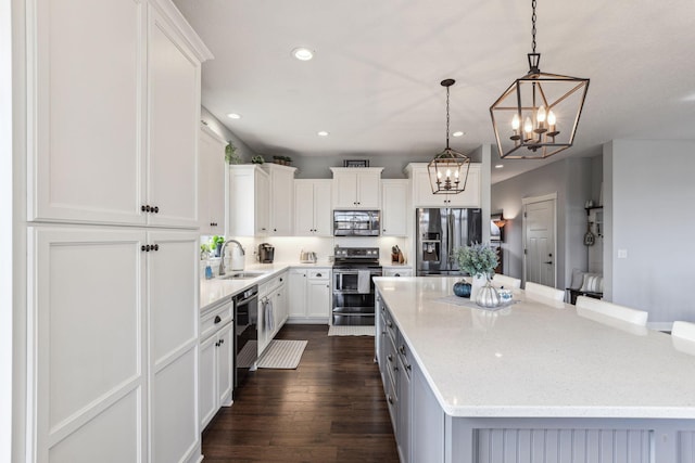 kitchen with dark hardwood / wood-style flooring, appliances with stainless steel finishes, a kitchen island, white cabinetry, and pendant lighting