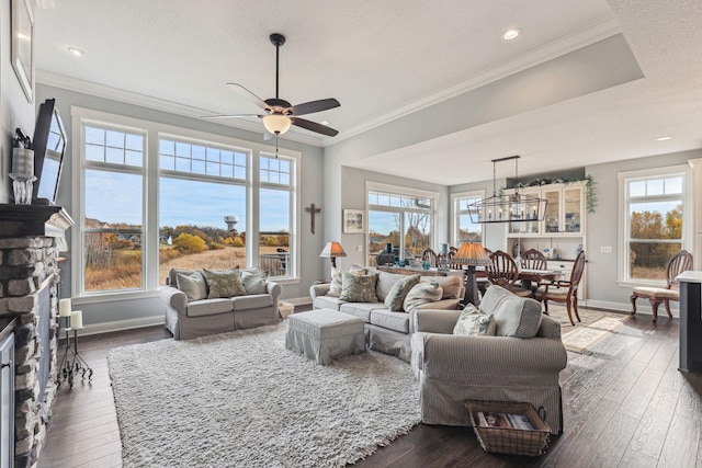 living room featuring a wealth of natural light, ornamental molding, a fireplace, and dark hardwood / wood-style flooring