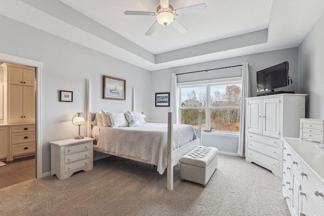 bedroom with light carpet, a tray ceiling, and ceiling fan