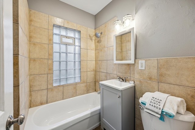 full bathroom with toilet, tiled shower / bath combo, vanity, and tile walls