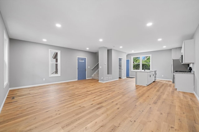 unfurnished living room featuring sink and light hardwood / wood-style flooring