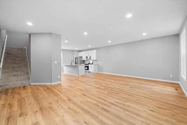 unfurnished living room featuring sink and light hardwood / wood-style flooring