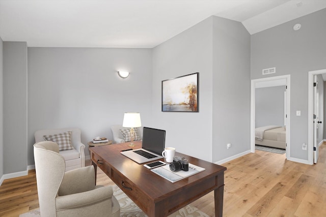 office space with high vaulted ceiling and light wood-type flooring