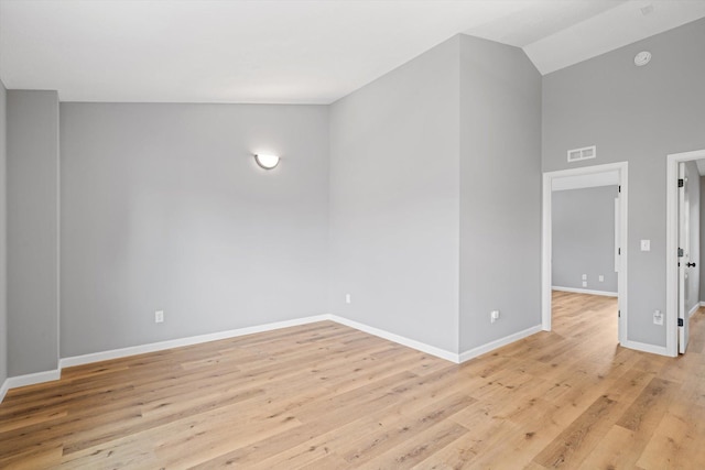 spare room featuring light wood-type flooring and vaulted ceiling