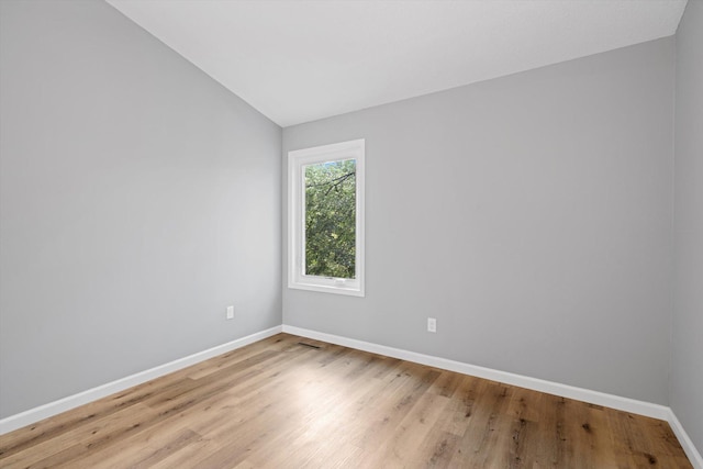 unfurnished room with vaulted ceiling and light wood-type flooring