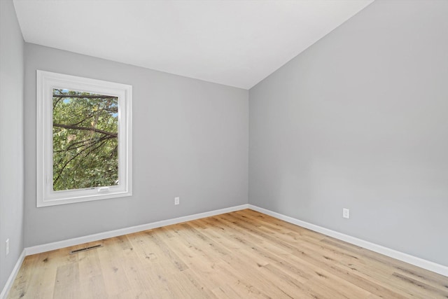 unfurnished room featuring lofted ceiling and light wood-type flooring