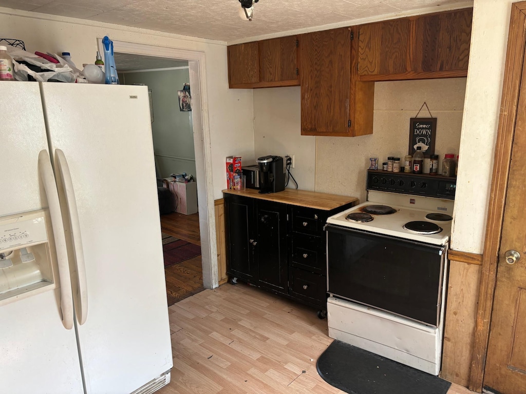 kitchen featuring a textured ceiling, light wood-type flooring, and white appliances
