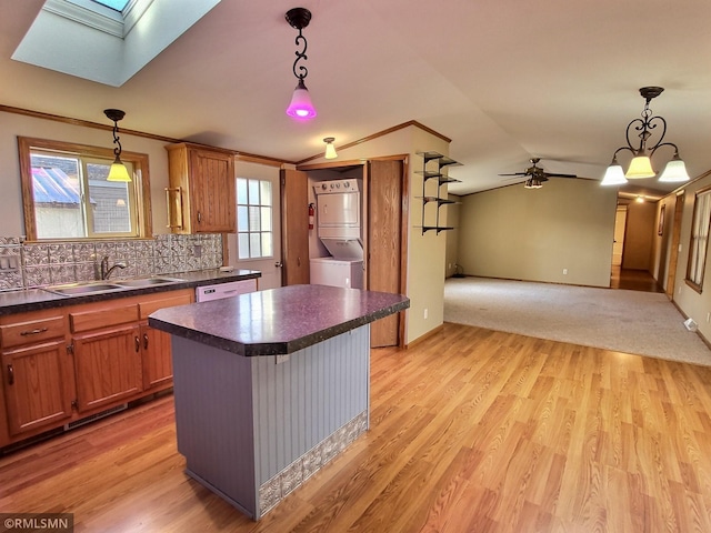 kitchen featuring stacked washing maching and dryer, decorative light fixtures, and light wood-type flooring