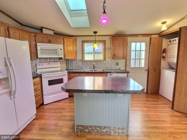 kitchen featuring stacked washer and dryer, decorative light fixtures, light wood-type flooring, white appliances, and a skylight