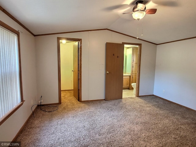 unfurnished bedroom featuring light carpet, ornamental molding, vaulted ceiling, ensuite bathroom, and ceiling fan