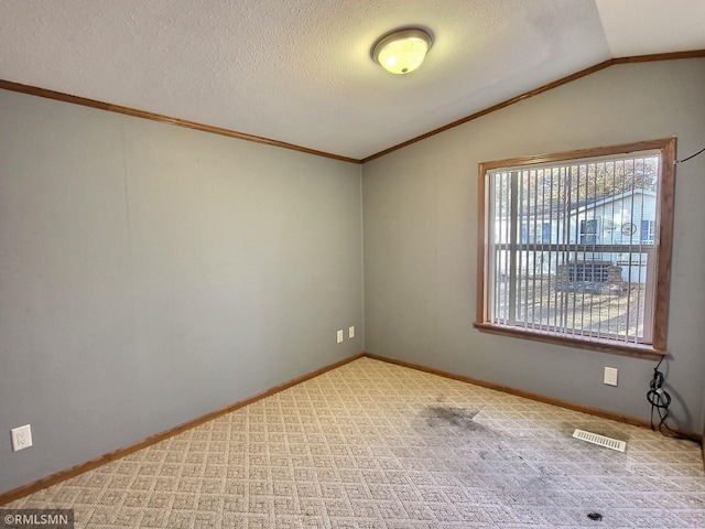 empty room with crown molding, a textured ceiling, vaulted ceiling, and light colored carpet