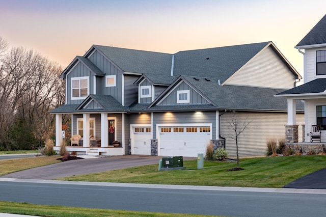 view of front facade with a garage, a lawn, and covered porch