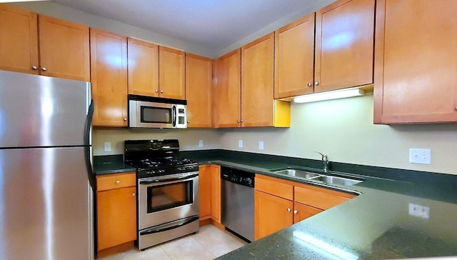 kitchen with appliances with stainless steel finishes, light tile patterned flooring, and sink