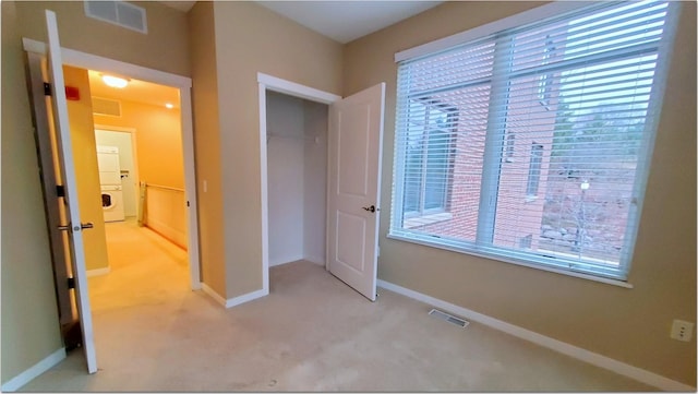 unfurnished bedroom featuring a closet, light carpet, multiple windows, and stacked washer and clothes dryer