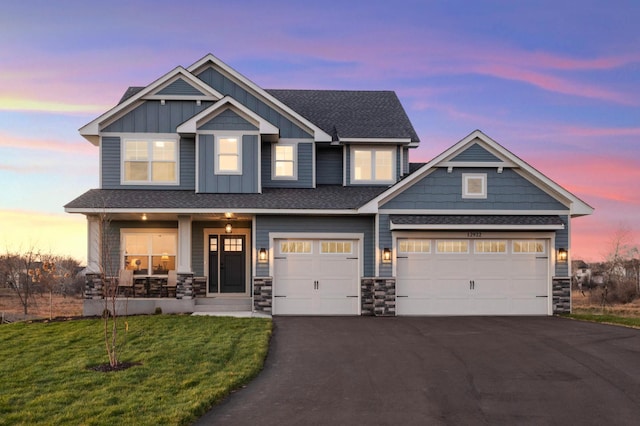 craftsman inspired home featuring a porch, a garage, and a lawn