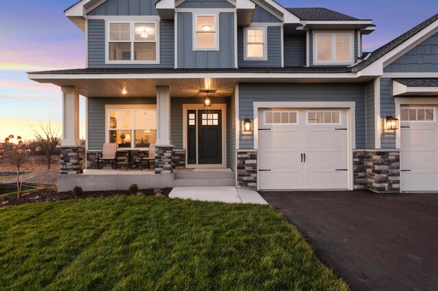 craftsman-style house with a porch, a yard, and a garage