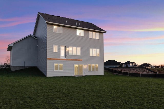 back house at dusk with a lawn