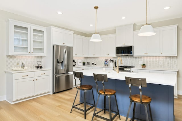 kitchen featuring decorative backsplash, appliances with stainless steel finishes, pendant lighting, and light hardwood / wood-style floors