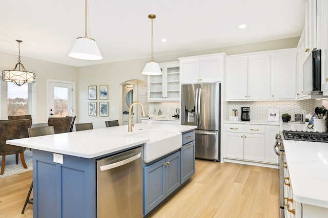 kitchen featuring appliances with stainless steel finishes, sink, pendant lighting, blue cabinetry, and a center island with sink