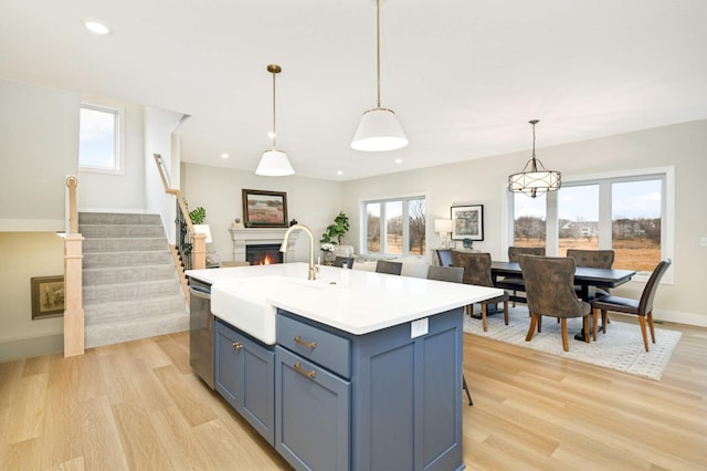 kitchen with sink, light hardwood / wood-style flooring, hanging light fixtures, and dishwasher