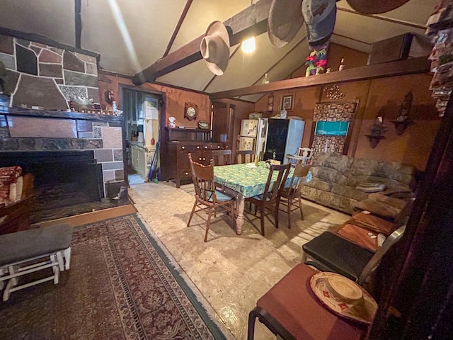 dining room with a stone fireplace and lofted ceiling