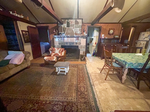 dining space featuring lofted ceiling with beams and a stone fireplace