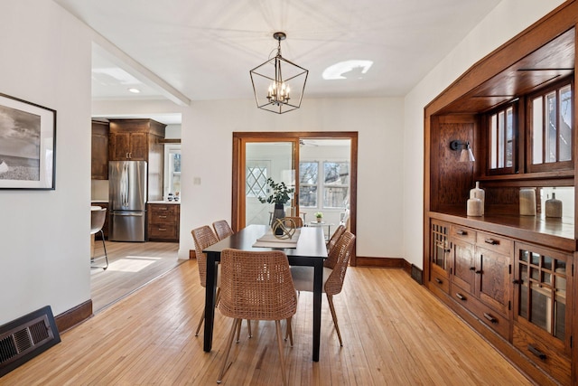 dining space with a notable chandelier, visible vents, light wood-type flooring, and baseboards