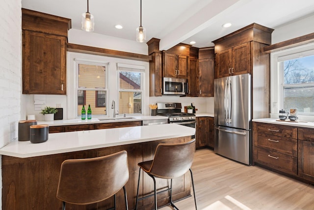 kitchen featuring a sink, a breakfast bar, light wood-type flooring, and stainless steel appliances