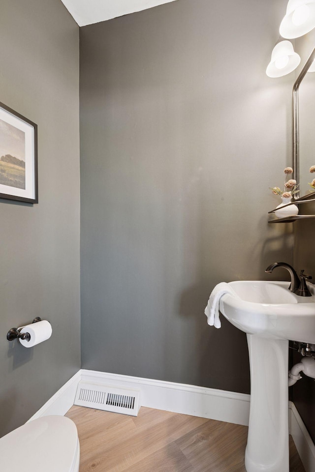 half bathroom with visible vents, baseboards, toilet, and wood finished floors