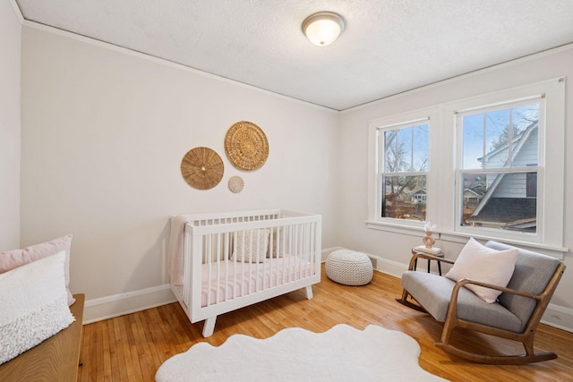 bedroom with a textured ceiling, baseboards, and wood finished floors