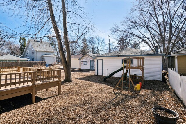 exterior space with a deck, an outbuilding, a playground, and fence