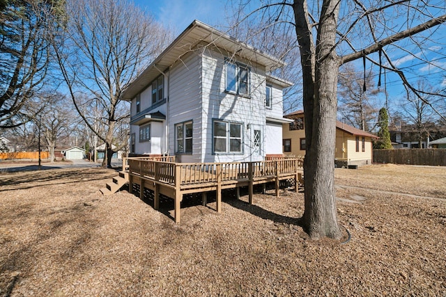 back of house featuring an outbuilding, fence, and a wooden deck