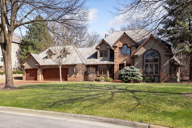 view of front of home featuring an attached garage, driveway, a front lawn, and stone siding