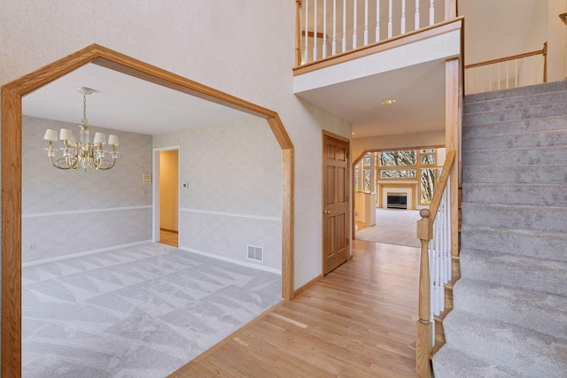 foyer entrance featuring visible vents, baseboards, a chandelier, wood finished floors, and stairway