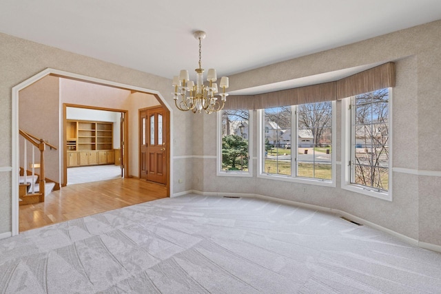 unfurnished dining area with stairway, a chandelier, baseboards, carpet flooring, and visible vents