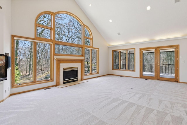 unfurnished living room featuring high vaulted ceiling, a fireplace with raised hearth, baseboards, carpet flooring, and visible vents