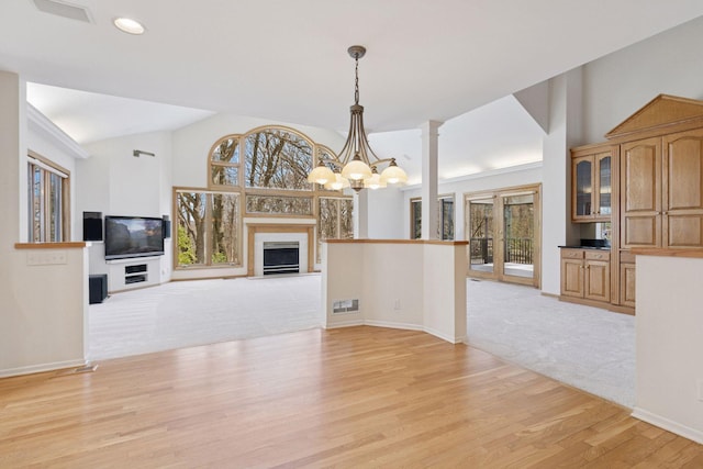unfurnished living room featuring a wealth of natural light, an inviting chandelier, visible vents, and light wood-style flooring