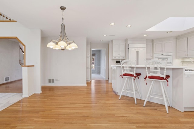 kitchen featuring light wood finished floors, a breakfast bar, and visible vents