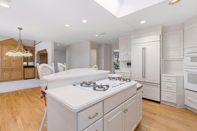 kitchen with light countertops, white appliances, an inviting chandelier, and an island with sink
