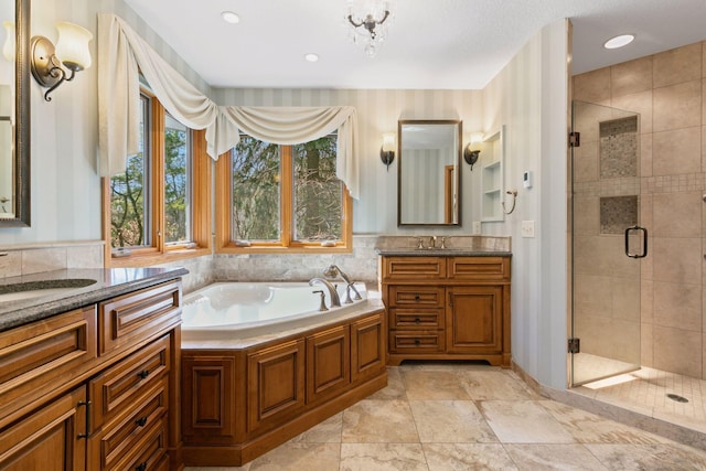 bathroom featuring a garden tub, two vanities, a sink, and a stall shower