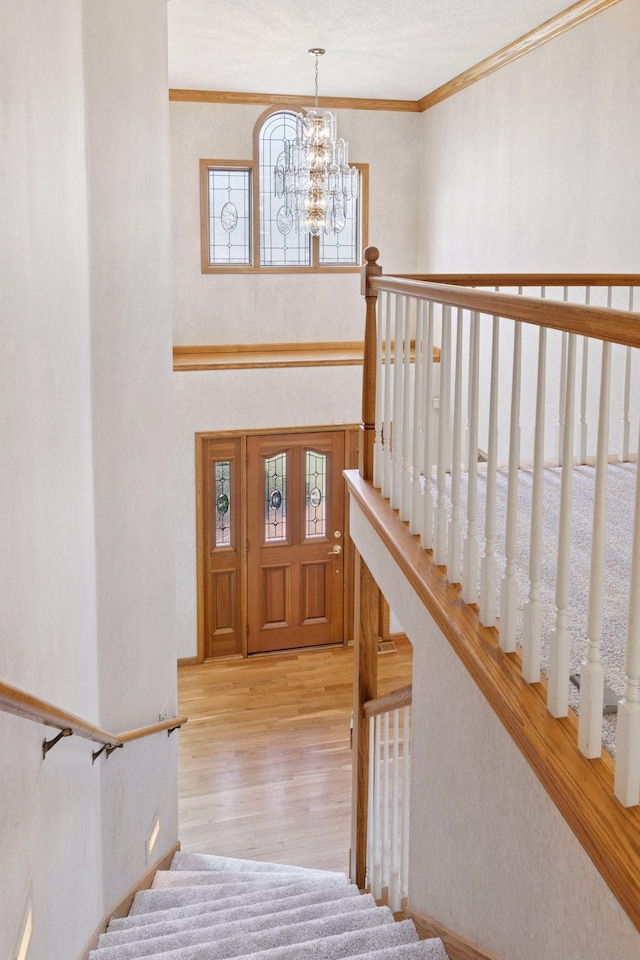 entryway featuring stairs, wood finished floors, a chandelier, and crown molding