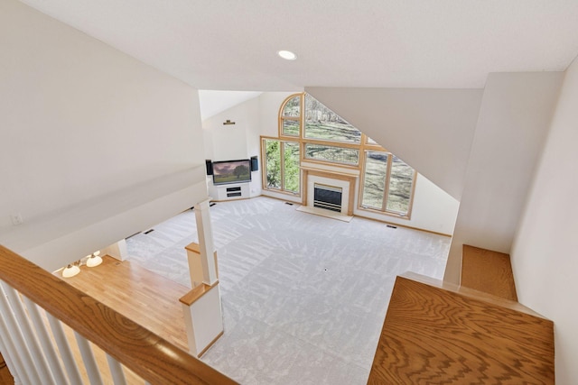 unfurnished living room featuring a glass covered fireplace, recessed lighting, visible vents, lofted ceiling, and carpet floors